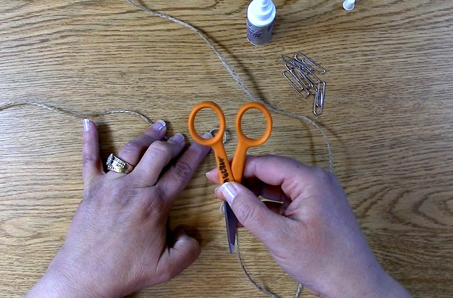 use scissors or an object to press the twine together with the adhesive